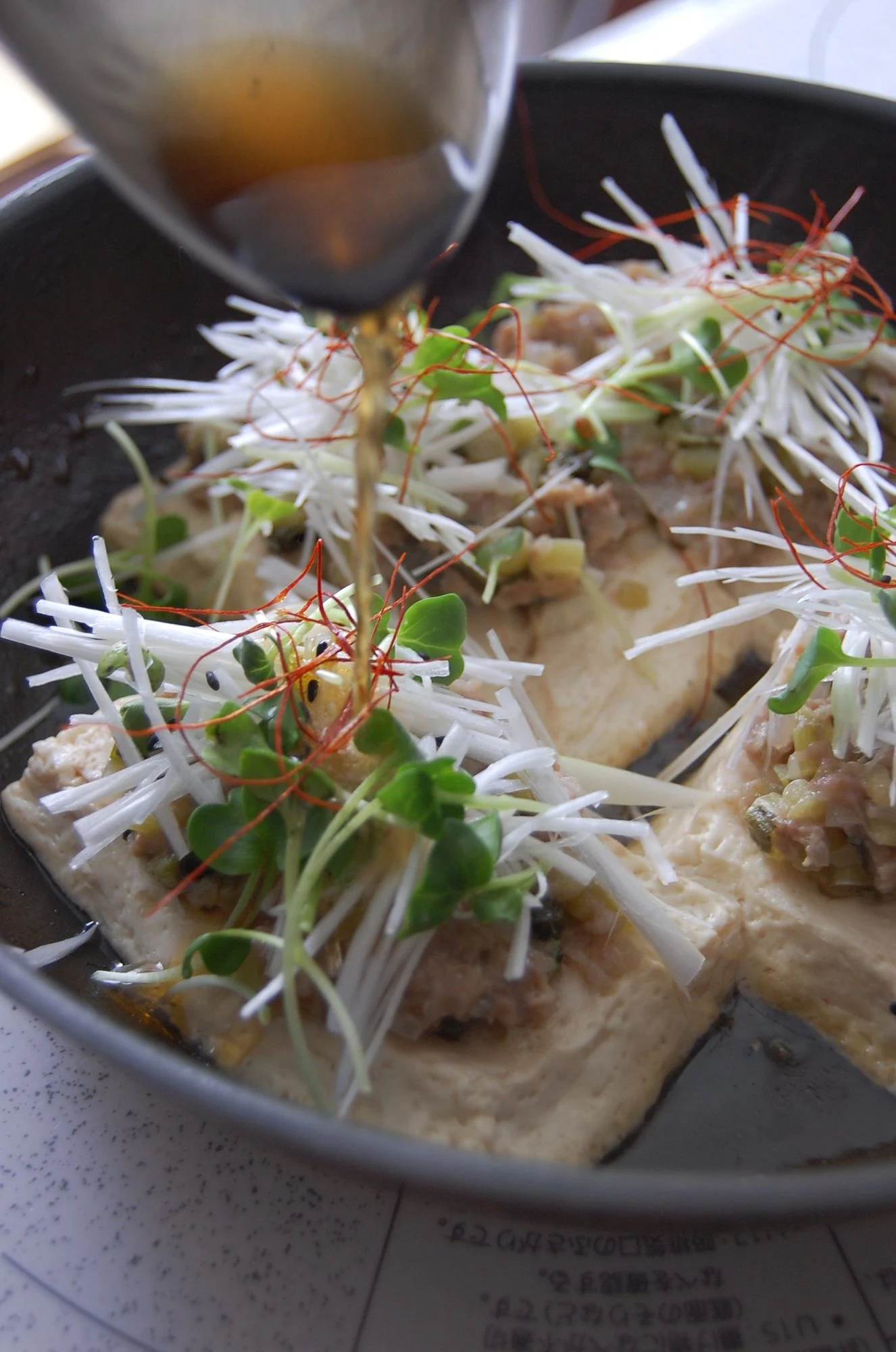 豆腐の料理にたれを回しかけるところ